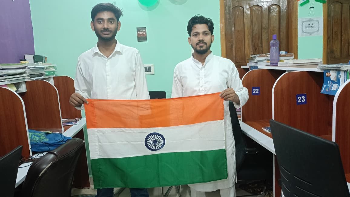 Two students holding the Indian flag between the study cabins